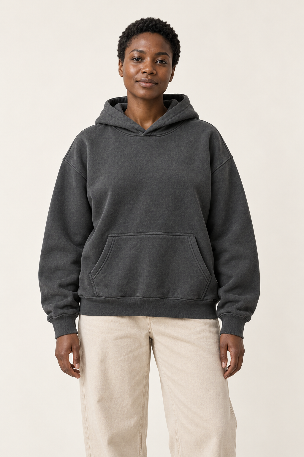 Adult woman wearing the COMMON FORM Women's Essential Hoodie in Charcoal.
