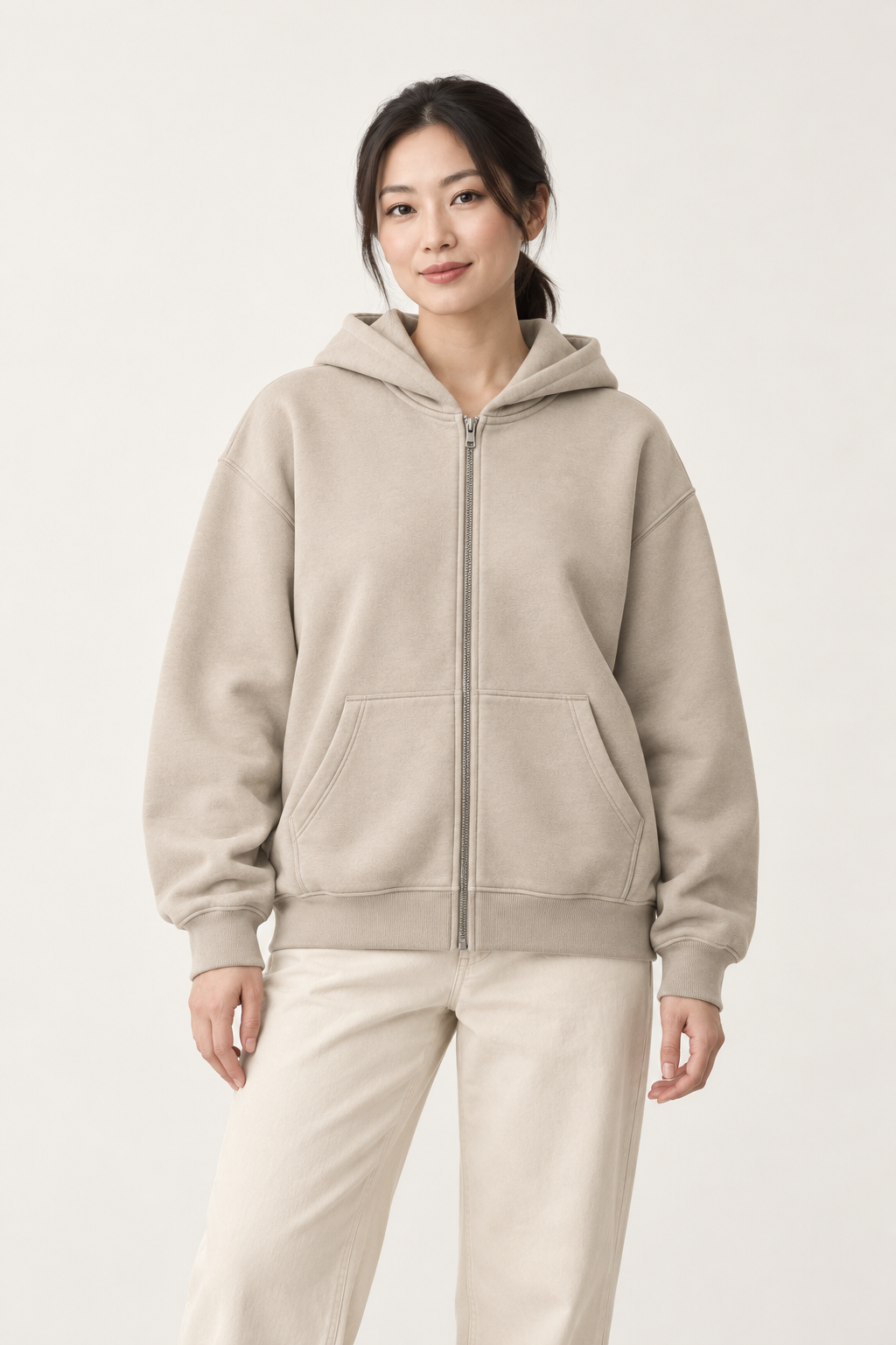 Adult woman wearing the COMMON FORM Women's Zip Through Hoodie in Stone.